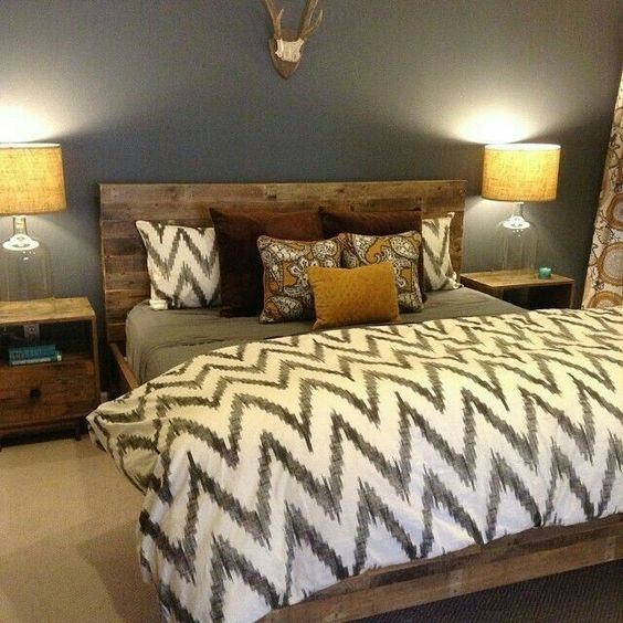 اتاق خواب دو نفره با تخت چوبی قهوه ای و فرش کرم رنگ که دارای روتختی و کوسن های طرح دار می باشد